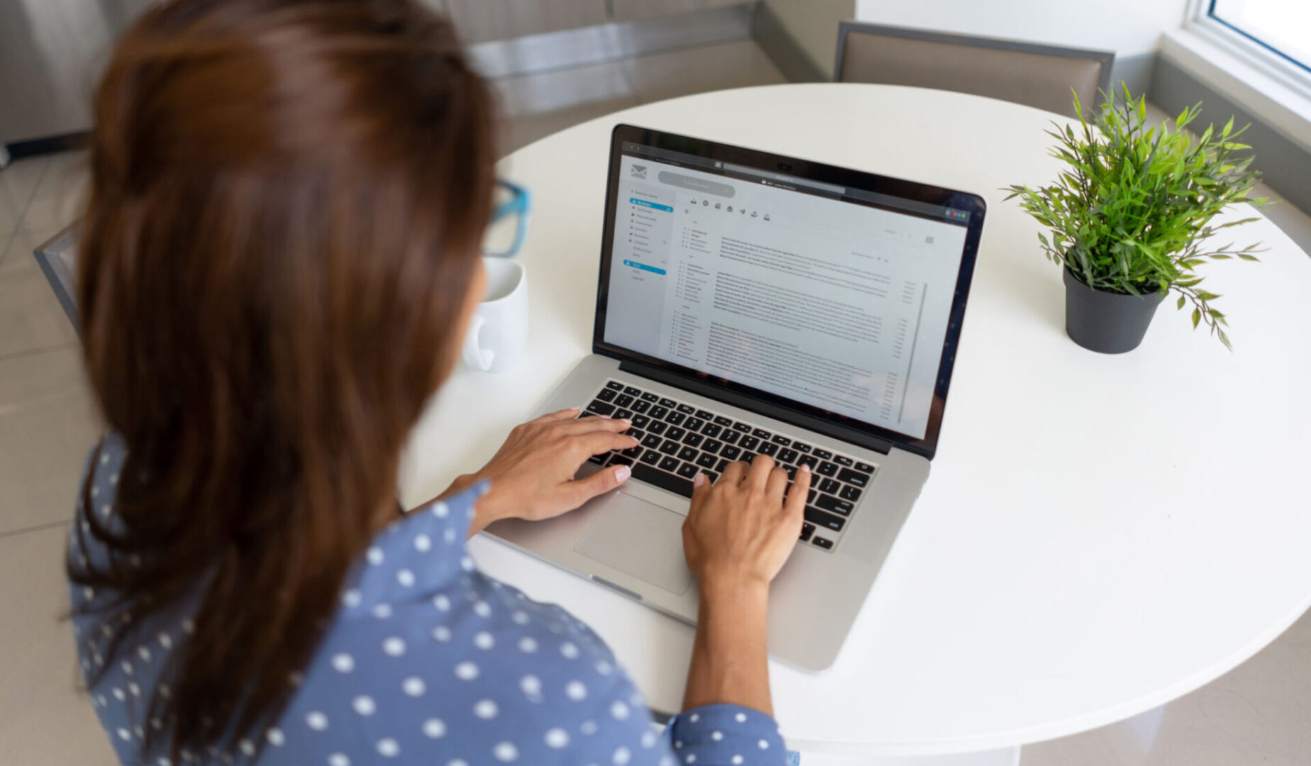 Woman typing on a laptop at table