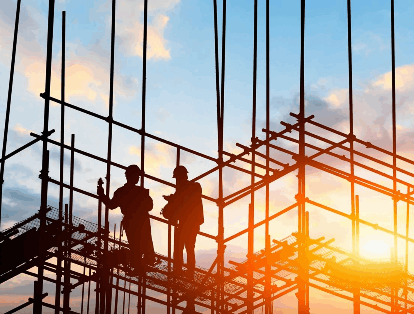 Construction workers silhouetted against sunset sky